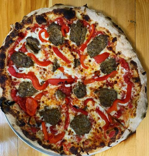A round pizza topped with meatballs, red peppers, and melted cheese on a golden crust.
