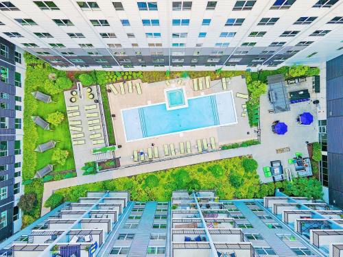 Aerial view of a modern apartment complex with a pool and lounge area surrounded by greenery and sun loungers.