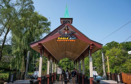 Entrance to Eagle Zip Adventure, featuring a wooden structure with a green spire and lush greenery in the background.