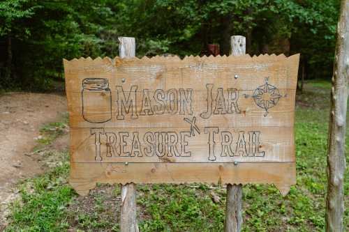 Wooden sign for "Mason Jar Treasure Trail" with a jar illustration and compass design, set in a wooded area.