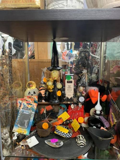 A display case filled with various decorative items, including a witch figurine, candles, and colorful trinkets.