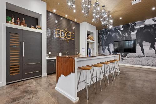 Modern kitchen bar area with stylish stools, sleek cabinetry, and a large wall mural of horses. Bright, inviting atmosphere.