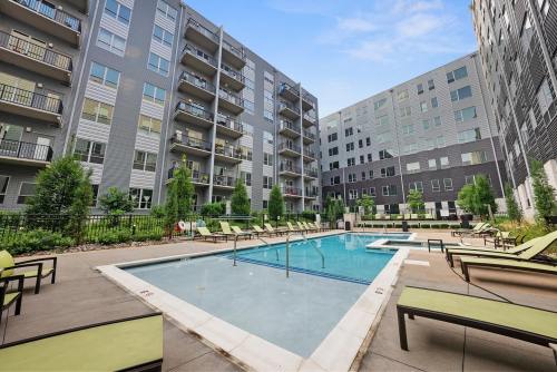 A modern apartment complex featuring a pool surrounded by lounge chairs and greenery.