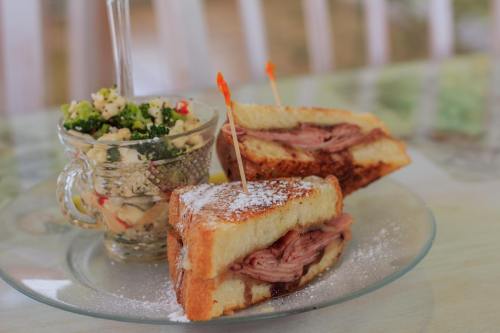 A plate with two sandwiches and a small bowl of salad, garnished with toothpicks and powdered sugar.