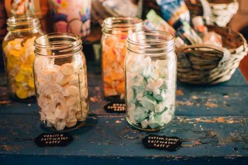 Jars of colorful saltwater taffy in a rustic setting, labeled with flavors like vanilla and cotton candy.