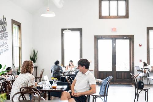 A bright café with people working at tables, featuring large windows and a relaxed atmosphere.