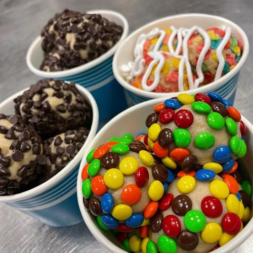 Four dessert cups: two with chocolate chip cookie dough balls, one with colorful cereal, and one with candy-coated treats.