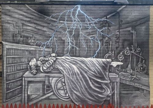 A mural depicting a woman lying on a table, surrounded by books and scientific equipment, with lightning striking above her.