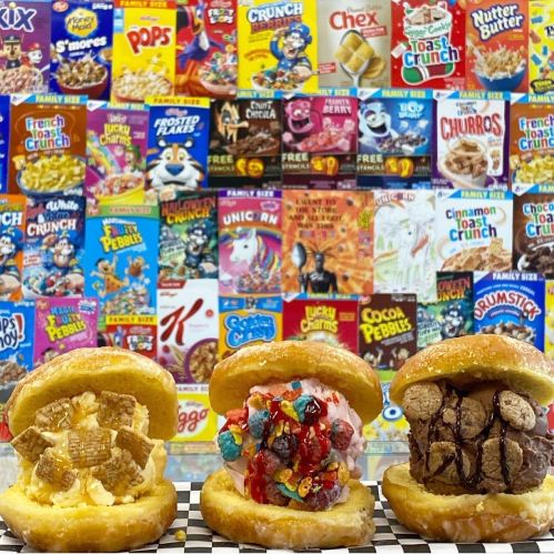 Three colorful ice cream sandwiches on a checkered surface, with a vibrant cereal box wall in the background.