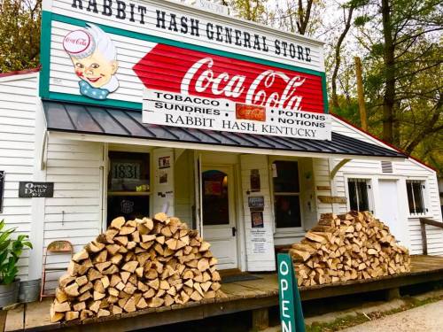 A quaint general store in Rabbit Hash, Kentucky, with a Coca-Cola sign and a stack of firewood in front.