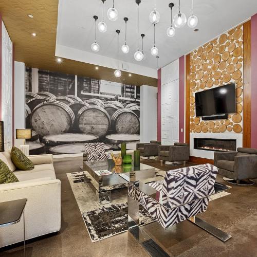 Modern lounge area with stylish furniture, a large wall mural of barrels, and decorative lighting fixtures.