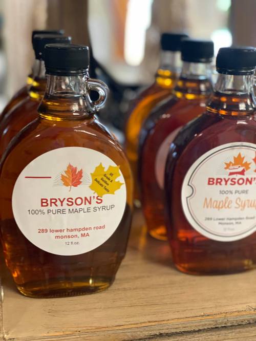 Bottles of Bryson's 100% pure maple syrup displayed on a shelf, featuring a leaf design on the labels.