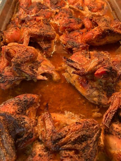 A tray of seasoned, roasted chicken pieces in a savory sauce, golden brown and crispy.