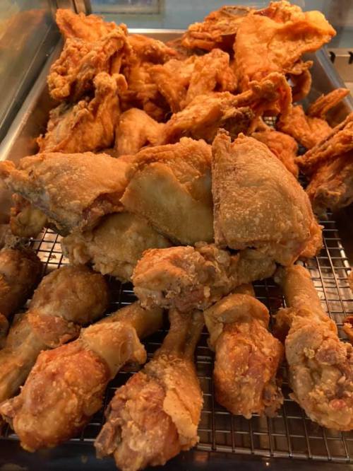 A close-up of a pile of crispy, golden-brown fried chicken pieces on a cooling rack.