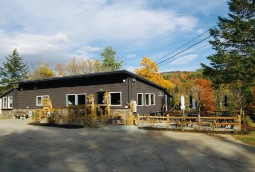 A cozy wooden building surrounded by colorful autumn trees and outdoor seating.