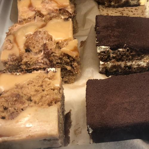 A tray of assorted layered desserts, including caramel and chocolate treats, with a rich, creamy texture.
