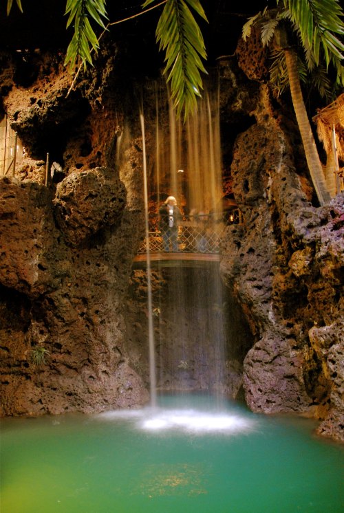 A serene waterfall cascades into a turquoise pool, surrounded by rocky formations and lush greenery.