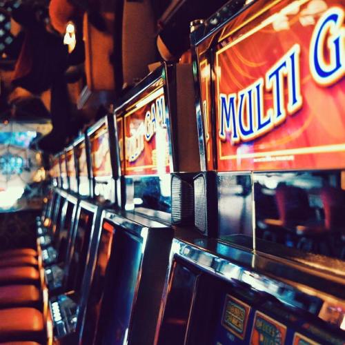 A row of illuminated slot machines with "MULTI GAME" signs in a dimly lit casino setting.