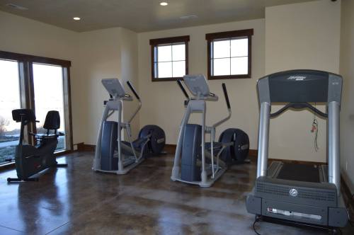 A home gym featuring two elliptical machines, a stationary bike, and a treadmill in a well-lit room.