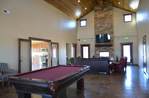 Interior of a spacious room featuring a pool table, stone fireplace, and seating area with wooden accents.