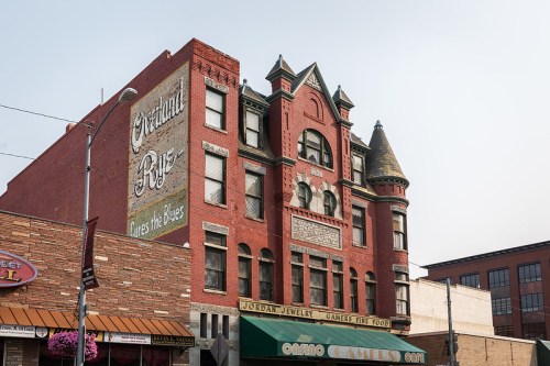 Historic red brick building with ornate architecture and a mural reading "Original Blues" in a city setting.