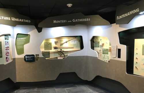 Exhibit wall featuring displays on culture, hunters and gatherers, and flintknapping techniques.