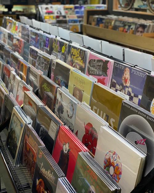 A display of various vinyl records arranged in rows, showcasing colorful album covers in a music store.