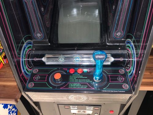 Close-up of an arcade game control panel featuring a joystick, buttons, and a blank screen.