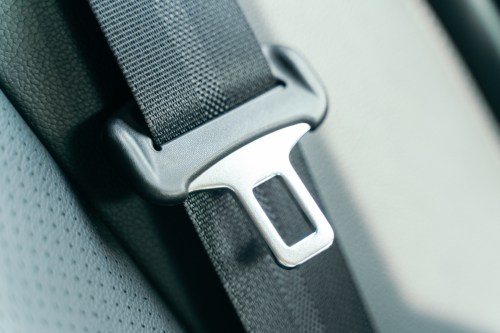 Close-up of a car seatbelt buckle on a textured fabric background.
