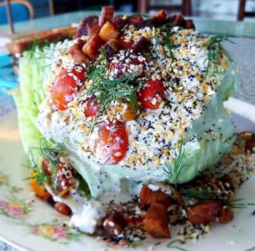 A vibrant salad featuring lettuce, cherry tomatoes, herbs, and a sprinkle of seeds, served on a decorative plate.