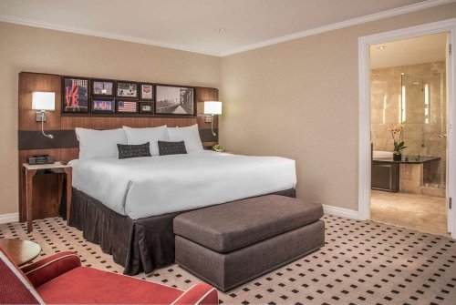 A modern hotel room featuring a king-sized bed, seating area, and an adjoining bathroom.