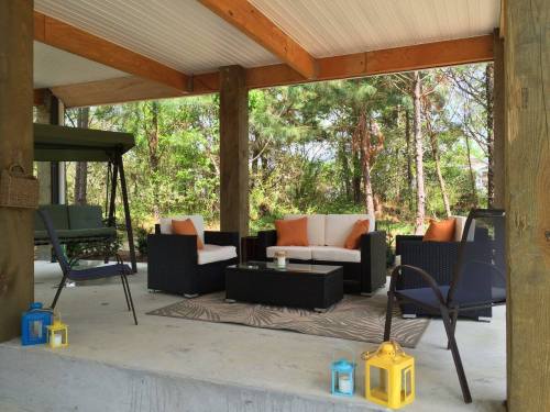 Cozy outdoor seating area with a sofa, chairs, and lanterns, surrounded by greenery.
