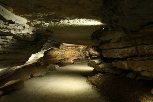 A dimly lit cave with rocky walls and a sandy path, showcasing natural formations and textures.