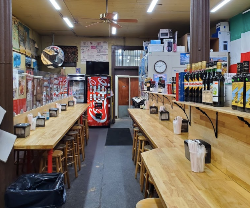 A cozy eatery with wooden tables, a soda machine, and shelves stocked with drinks, featuring a warm, inviting atmosphere.