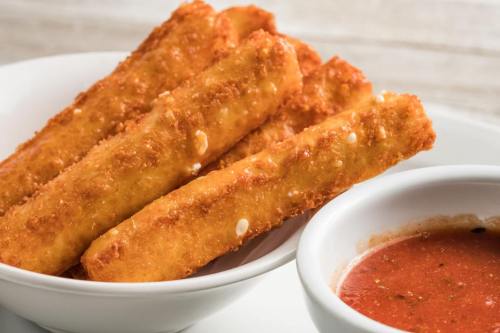 A bowl of crispy, golden-brown fried sticks served with a side of marinara sauce.