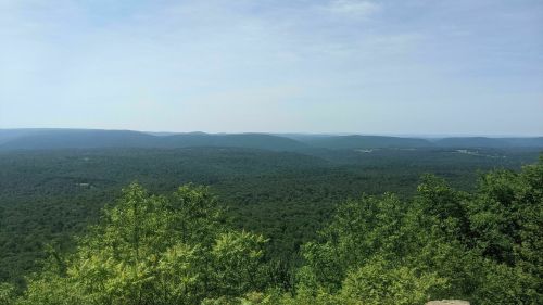 A panoramic view of lush green mountains under a clear sky, showcasing a serene natural landscape.