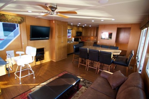 Interior of a modern, spacious living area with a kitchen, dining table, and comfortable seating. Bright and well-lit.
