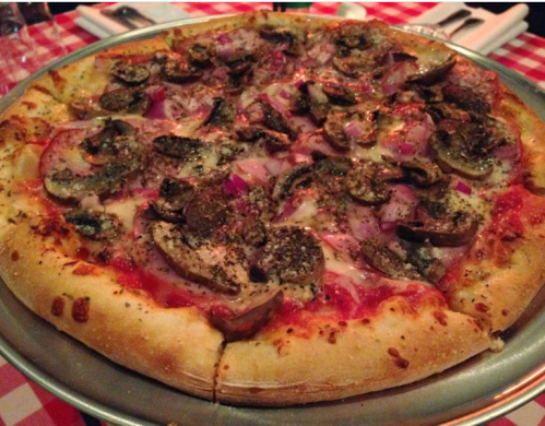 A freshly baked pizza topped with mushrooms, onions, and herbs on a silver serving tray.