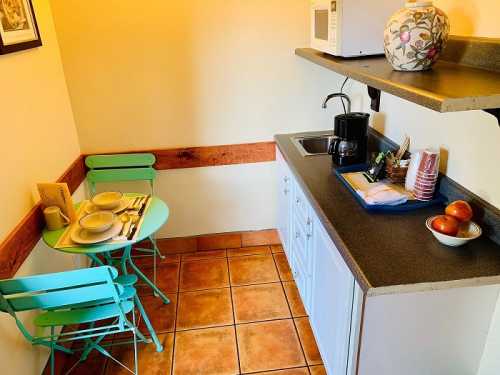 Cozy kitchen nook with a small table, two chairs, coffee maker, and microwave, featuring a warm color palette.