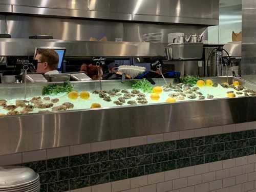 A seafood display featuring oysters and lemons in a restaurant setting, with a chef visible in the background.