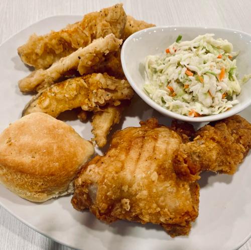 A plate of fried chicken, hushpuppies, and coleslaw, with a biscuit on the side.