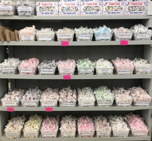 A display of colorful saltwater taffy in various flavors, organized in baskets on shelves.
