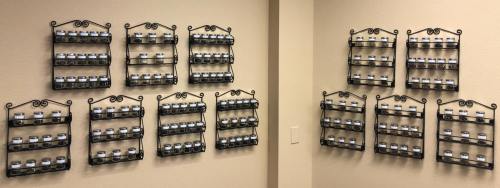 A wall display featuring multiple black metal shelves holding small jars, organized in a neat grid pattern.
