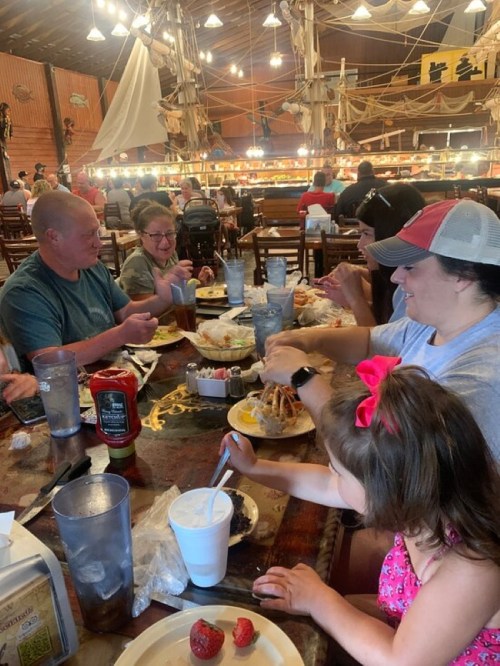 A group of people enjoying a meal together at a restaurant, with plates of food and drinks on the table.