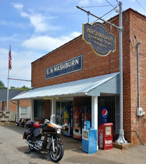 A brick general store with a sign reading "E.N. Washburn" and a motorcycle parked in front.