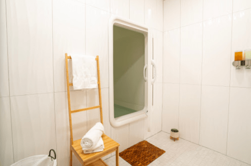 A clean, modern bathroom featuring a shower, towel rack, and a small plant on the floor.
