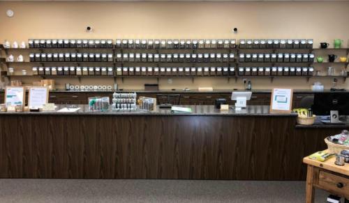 A retail counter with shelves of jars and containers filled with various products in a well-organized store.