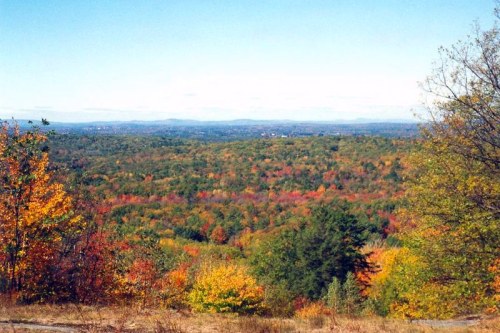 A panoramic view of a vibrant autumn landscape with colorful trees and a clear blue sky.