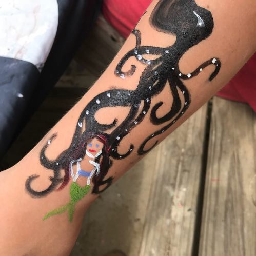 A painted arm featuring an octopus and a mermaid design in vibrant colors.