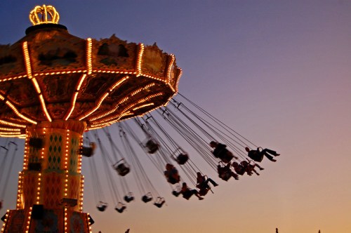 A colorful swing ride at dusk, with riders soaring against a vibrant sunset sky.